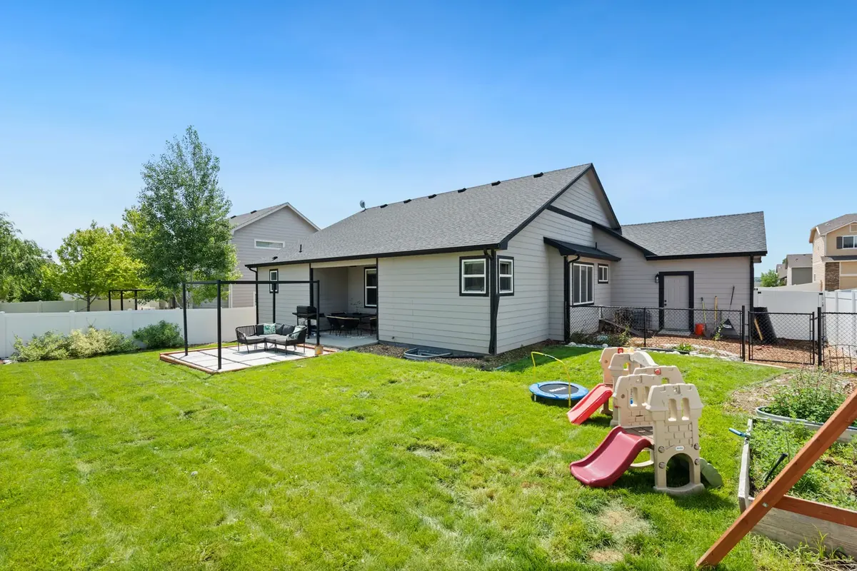 A plain suburban back garden with a small concrete slab, patchy lawn and play equipment