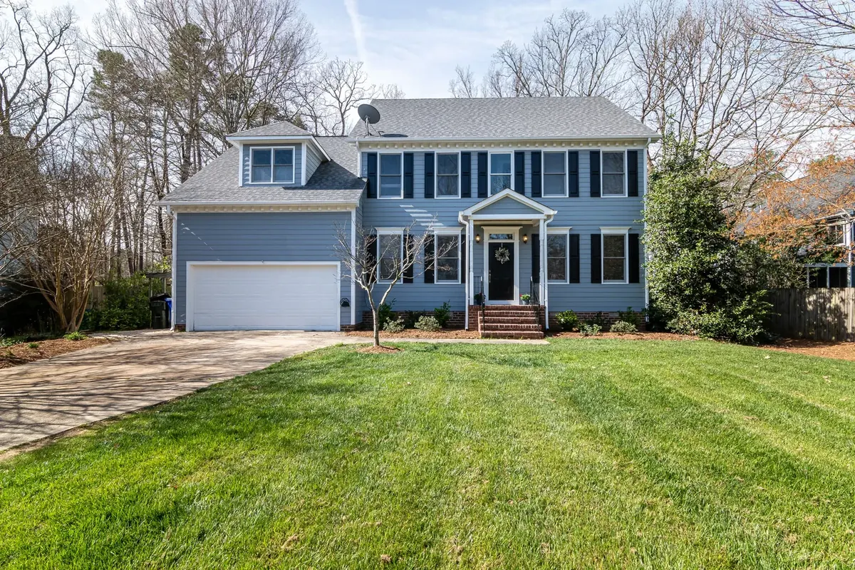 A blue colonial house with a plain mown lawn and no planting