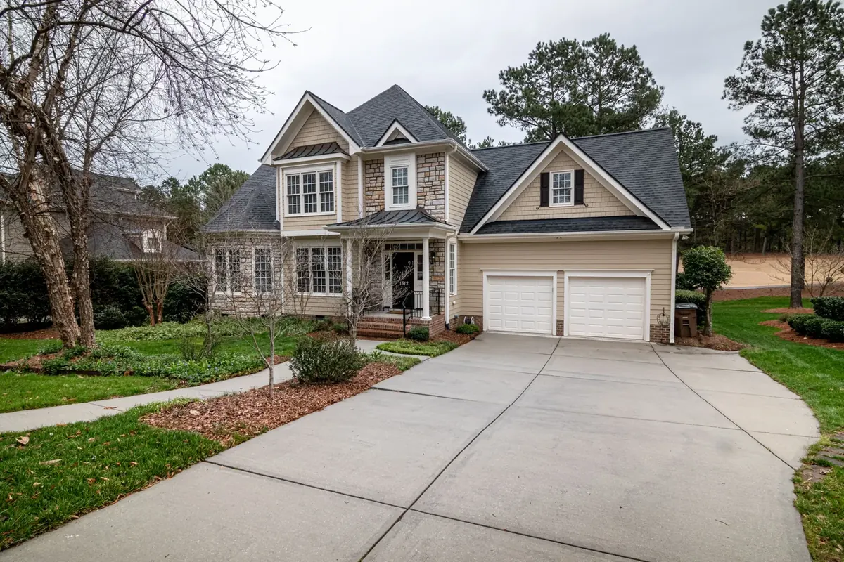 A large house with a wide concrete driveway and a thin strip of mulch