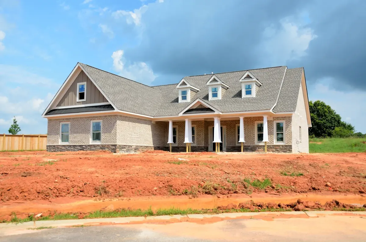 A newly built house standing on raw graded earth with no landscaping
